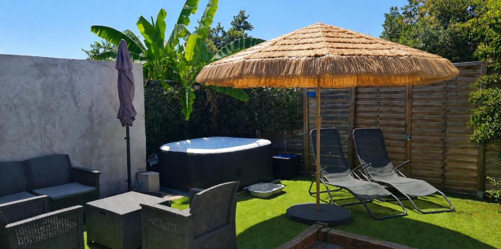 an umbrella and chairs and a tub in a yard at Beau logement avec terrasse, jacuzzi et terrain de pétanque privatif à 5 minutes de la plage in Audenge