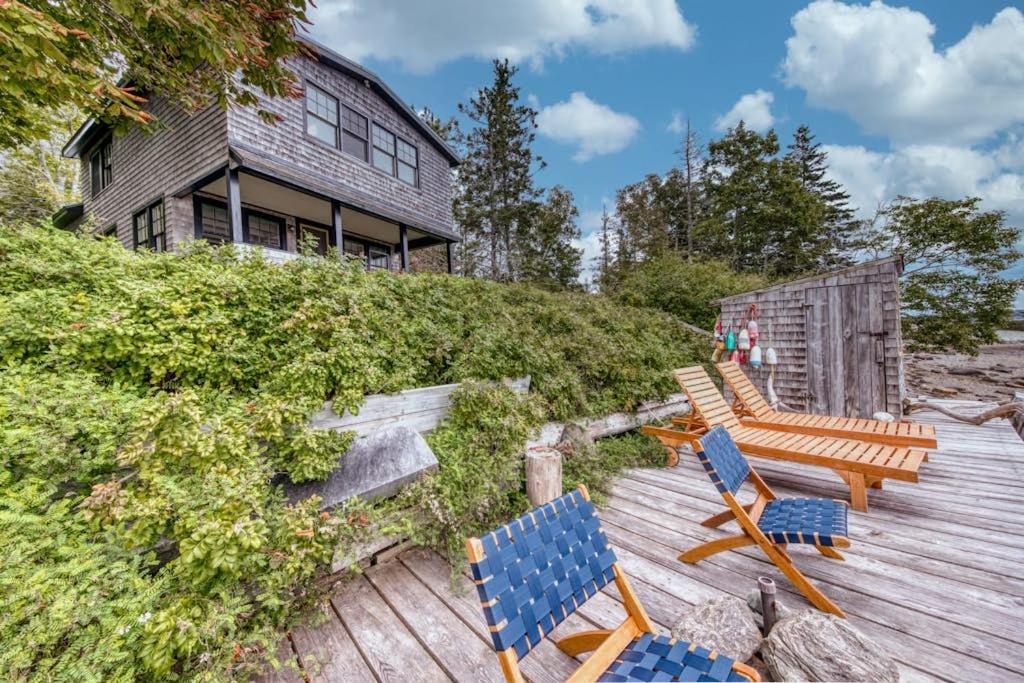 a group of chairs sitting on a wooden deck at Waterfront dog-friendly cottage with amazing views, deck, grill, & washer/dryer in Cushing