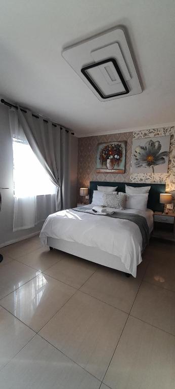 a bedroom with a large white bed and a window at Naliya Guest house in Cape Town