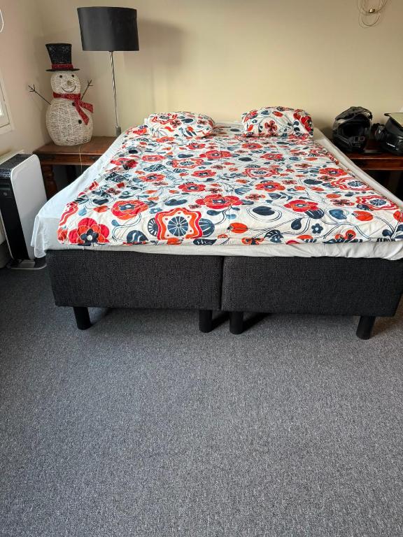 a bed in a bedroom with a flowered blanket on it at YKI Room in Oulu