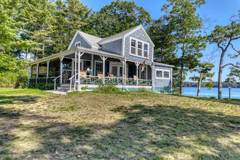 a house on the shore of a body of water at Spacious Waterfront Estate & Cabins W/ Porch, Fireplace, Kayaks & Free WiFi in Brunswick