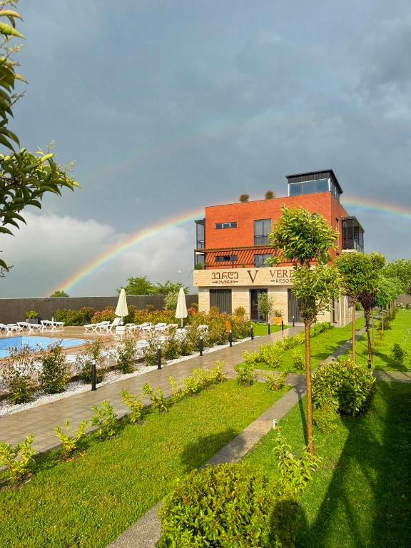 a rainbow in the sky over a building with a garden at Verde Resort in Ikalto