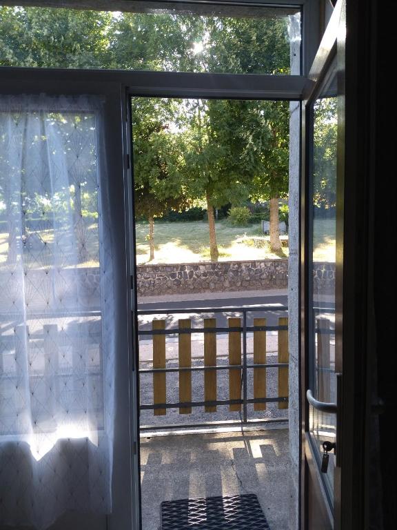 an open door to a porch with a view of a park at Les sources de la Loire 2 in Sainte-Eulalie