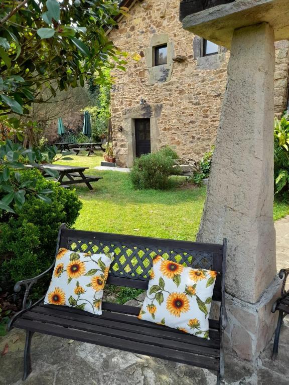 a bench with two pillows on it in a yard at Vega in Muñás