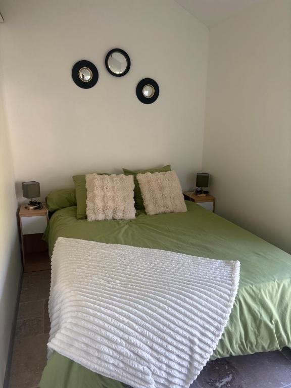 a bedroom with a green bed with two clocks on the wall at Ty Lochois in Loches