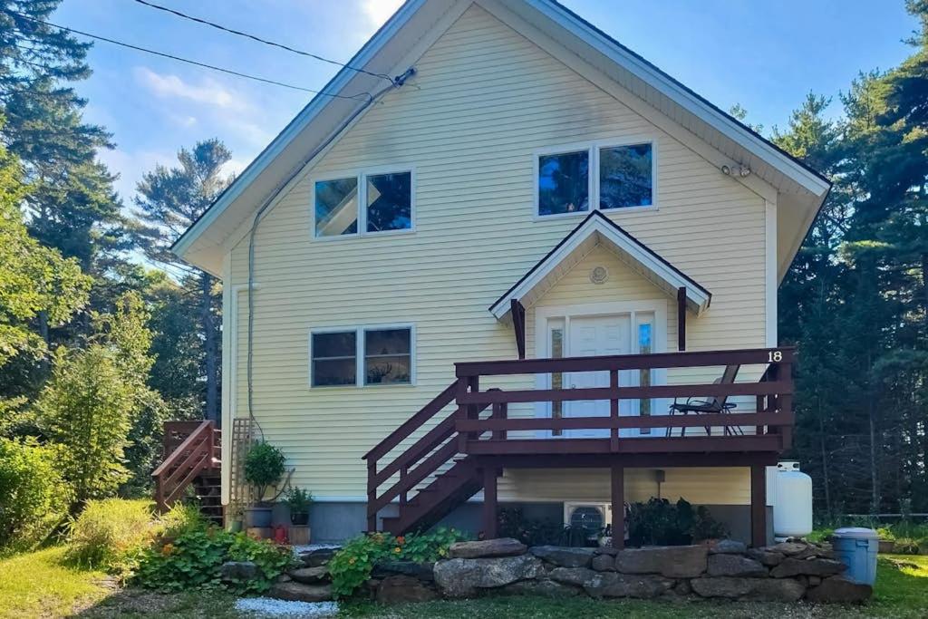 a house with a large deck on the front of it at Sunny coastal retreat with deck, grill, beach, dock, & ocean access in East Boothbay