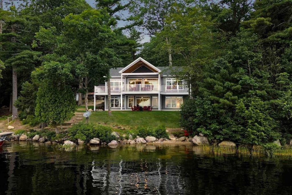 a large house on the shore of a body of water at Elegant lakefront home near Bar Harbor & Acadia with modern kitchen, lake views in Orland
