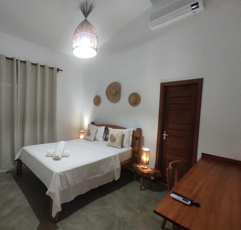 a bedroom with a large white bed and a table at Suítes em praça pontal de Maceió in Fortim