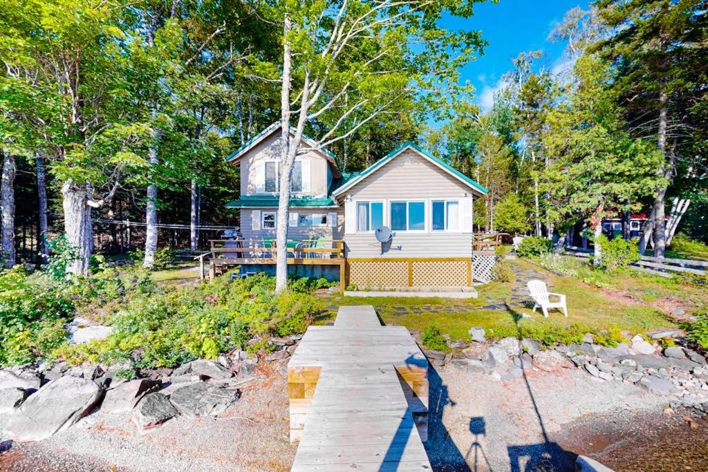 a small house in the middle of a yard at Vintage lakefront cabin with incredible water views, private dock & pebble beach in The Highlands
