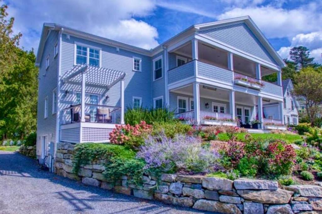 a large house with a stone retaining wall at Elegant home with veranda & water view, walk to downtown Boothbay Harbor in Boothbay Harbor