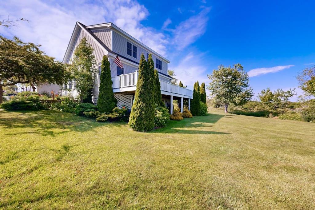 a large house with a flag on a yard at Oceanfront home with dock, beautiful deck & firepit - steps to the beach in Harpswell Center