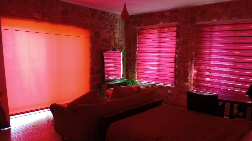 a room with pink blinds and a table and chairs at Khalle Lodge in Dayr al Qamar