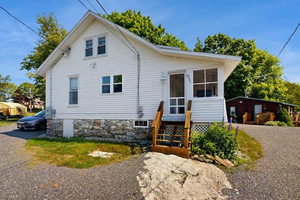 a white house with a car parked in front of it at Coastal charmer with screened-in porch, grill, & AC in Boothbay Harbor