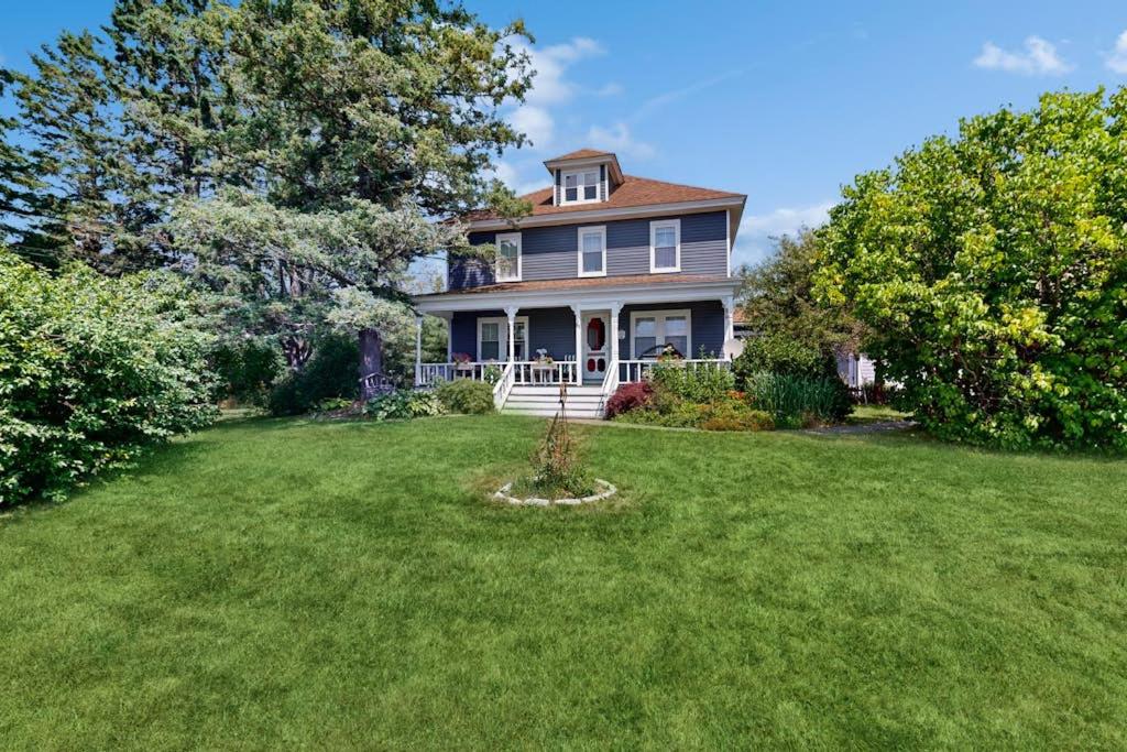 a large house with a yard with green grass at Charming Coastal Retreat with Ocean Views, Porch and Private Cabin in Sullivan