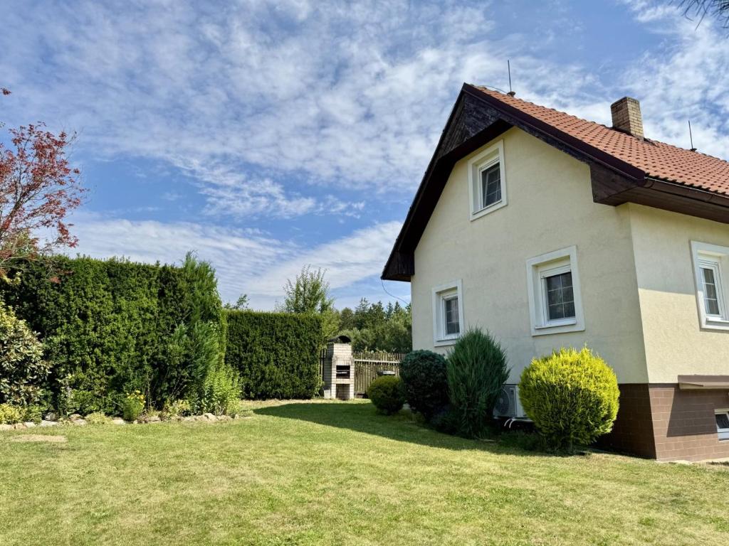 a white house with a yard and bushes at Cozy Family Retreat in a Quiet Village in Křešín