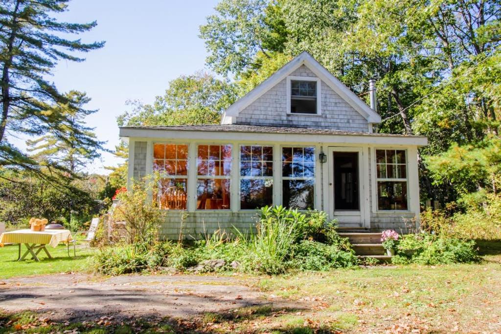 a small house with a garden and a table at Charming Bayview Cottage with Deck, Firepit, Garden - 200 in East Harpswell