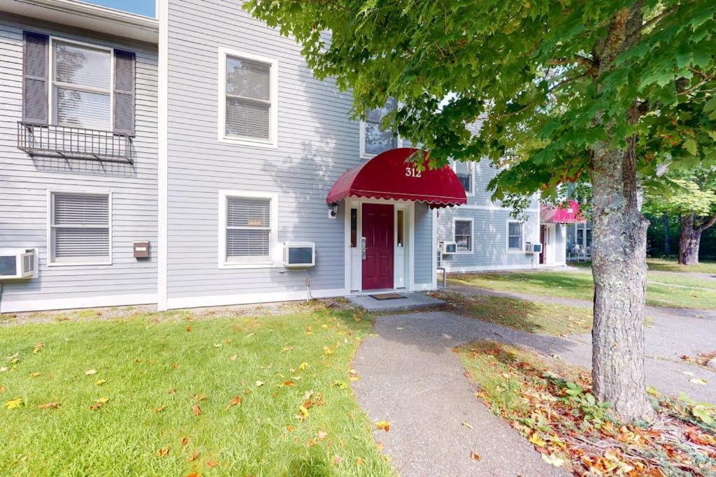 a white house with a red door and a tree at Townhome w/ Bonus Loft, High-Speed WiFi, Partial AC & Full Kitchen in Bar Harbor