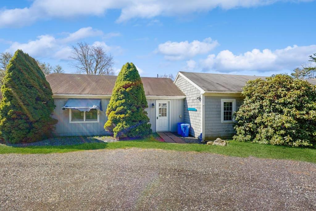 a house with two large trees in front of it at Charming, single-level getaway with a full kitchen, fast WiFi, & grassy yard in Boothbay