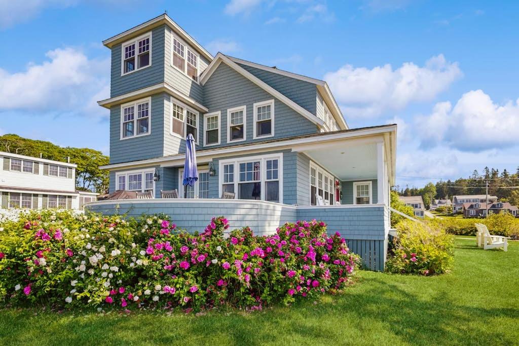 a blue house with flowers in the yard at Oceanfront home incredible ocean views, deck & location in Boothbay