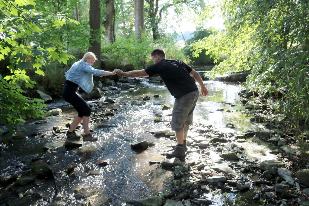 a man and a woman crossing a stream at Gästehaus Laßbruch in Extertal