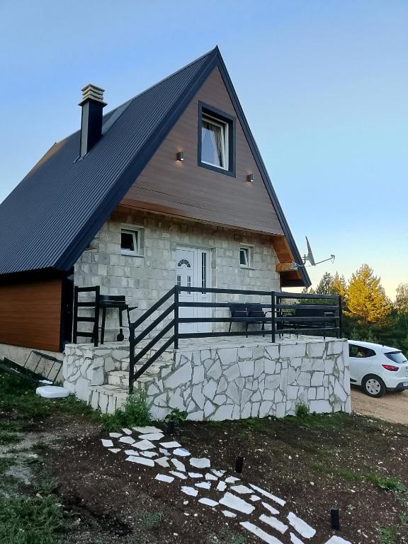 a house with a black roof and a stone wall at House Vasilije in Žabljak