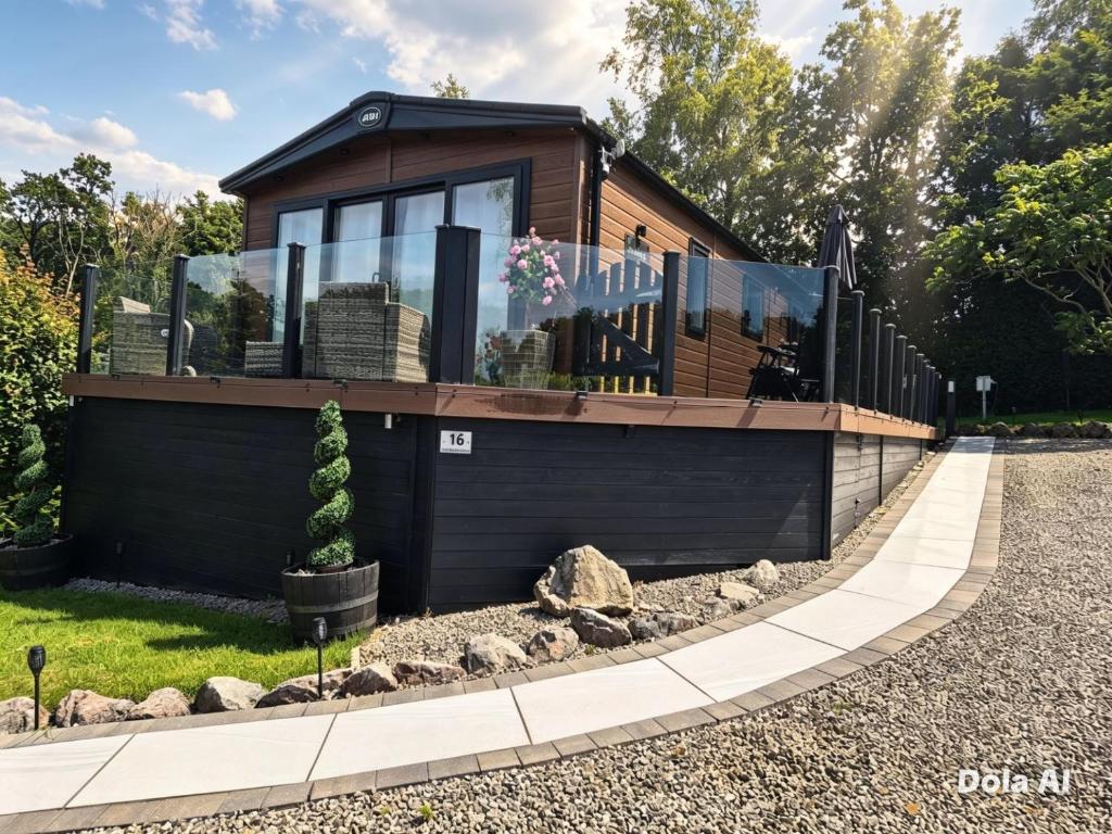 ein kleines Haus mit Glasfenstern an einer Einfahrt in der Unterkunft The Lodge-Static Holiday Lodge in Carnforth