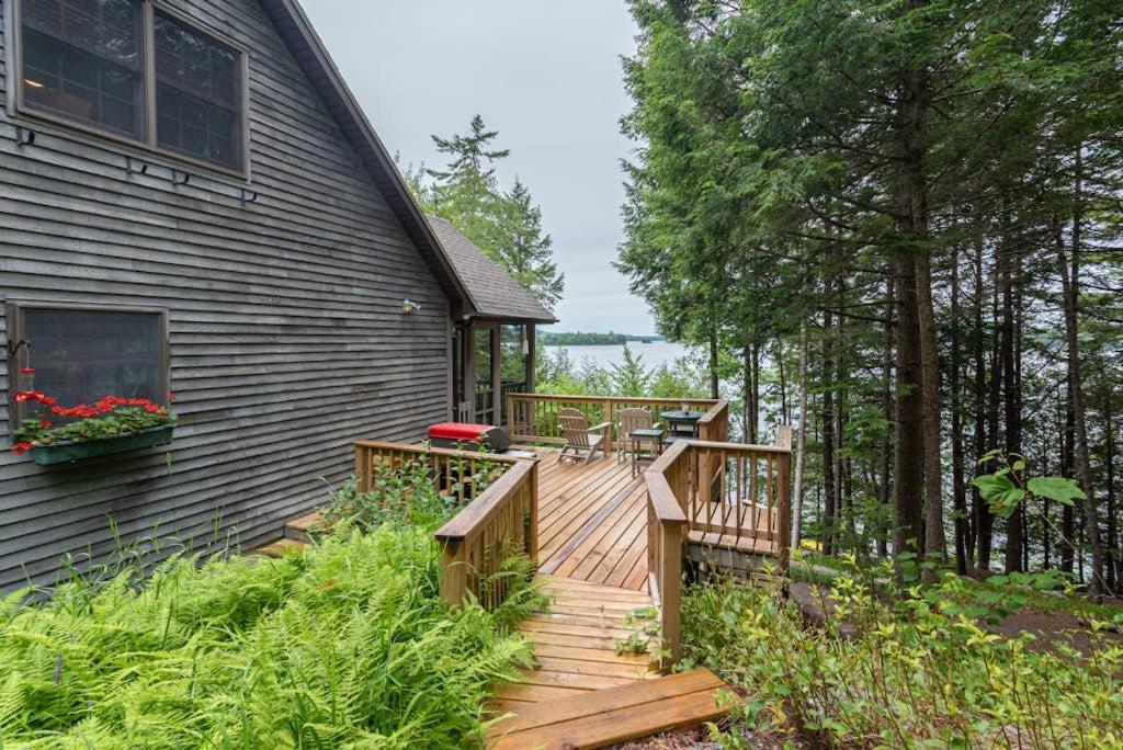a wooden deck on the side of a house at Gorgeous lakefront home w/ dock, canoe, kayaks & lake/forest views in Ellsworth