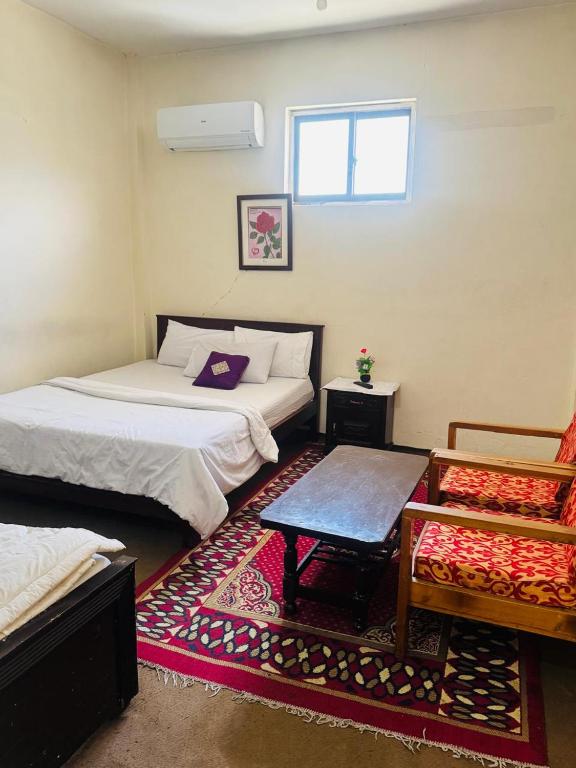 a room with two beds and a rug at Yasin Holiday Hotel in Gilgit
