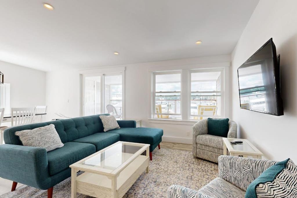 a living room with a blue couch and a table at Elegant Oceanfront Condo with Stunning Harbor Views & Spectacular Sunsets in Boothbay Harbor