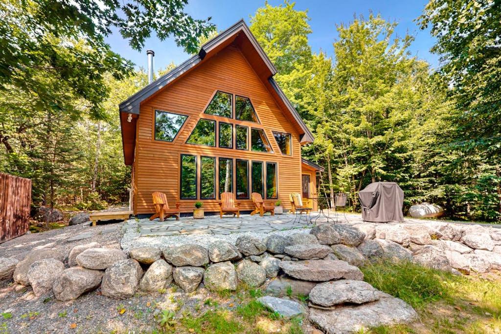 a log cabin in the woods with a stone wall at The Cabin on 32 wooded acres - tranquil new-build with sauna & forested views in Franklin
