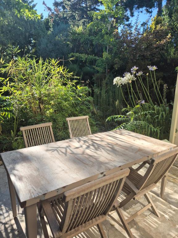 a wooden picnic table with two chairs in a garden at La Biro in Pornic