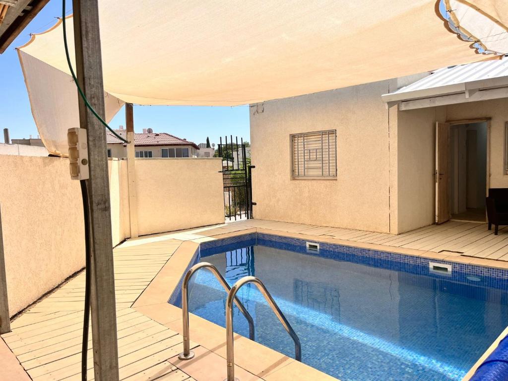a swimming pool with an umbrella on top of a house at וילה אושר in Mitzpe Ramon