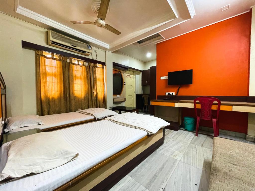 a bedroom with two beds and a desk with a tv at Hotel Haven in Agartala
