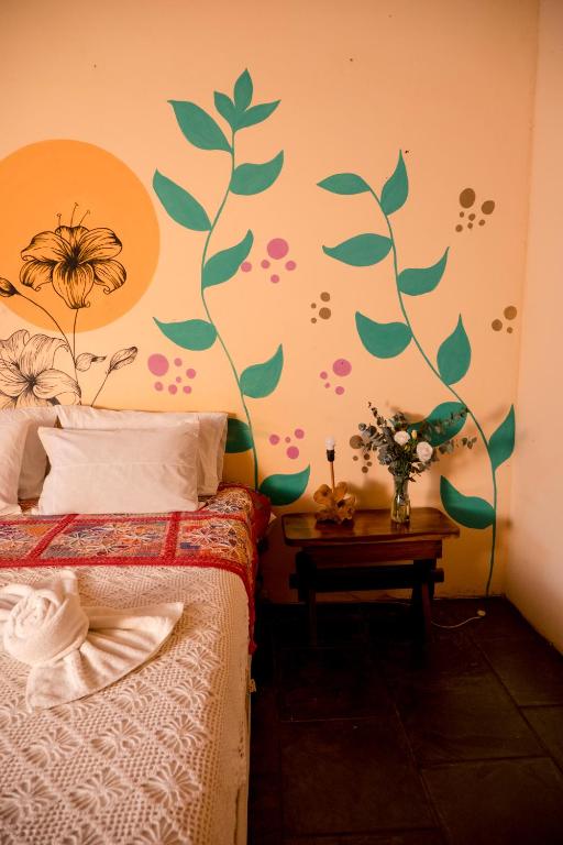 a bedroom with a bed with a flower mural on the wall at Pousada Templo Aláfia in Vera Cruz de Itaparica