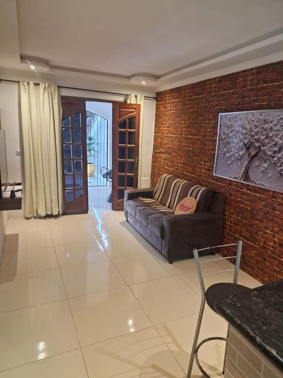 a living room with a couch and a brick wall at espaço inteiro no bairro mais tranquilo de gravatá in Gravatá