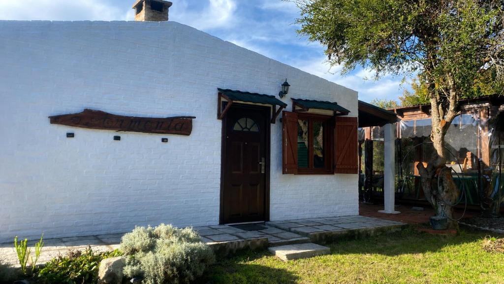 a white building with a door and a sign on it at Armonía in Villa Serrana