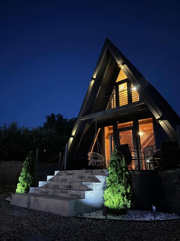 ein Haus mit einer Treppe davor bei Nacht in der Unterkunft Ocna Frame - A Frame cu Jacuzzi si Terasa in Ocna-Mureşului