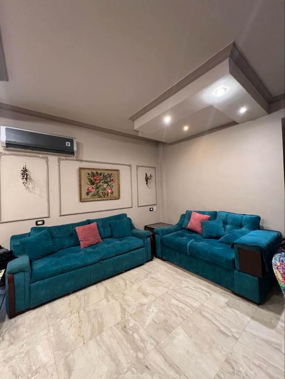 a living room with two blue couches at Kendaw home in Hihyā