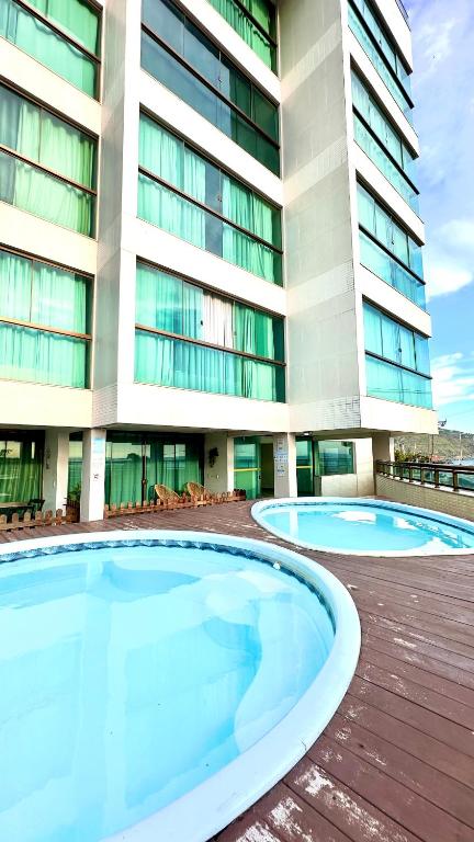 two large swimming pools in front of a building at Studios Praia Grande - VISTA MAR in Arraial do Cabo