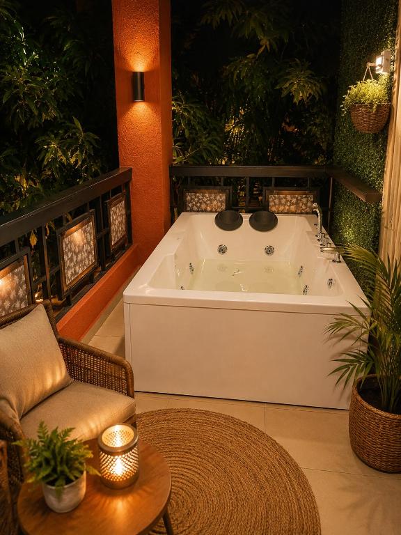 a bath tub in a room with a chair and a table at Jacuzzi Room in a shared Villa with Swimming pool in Thane