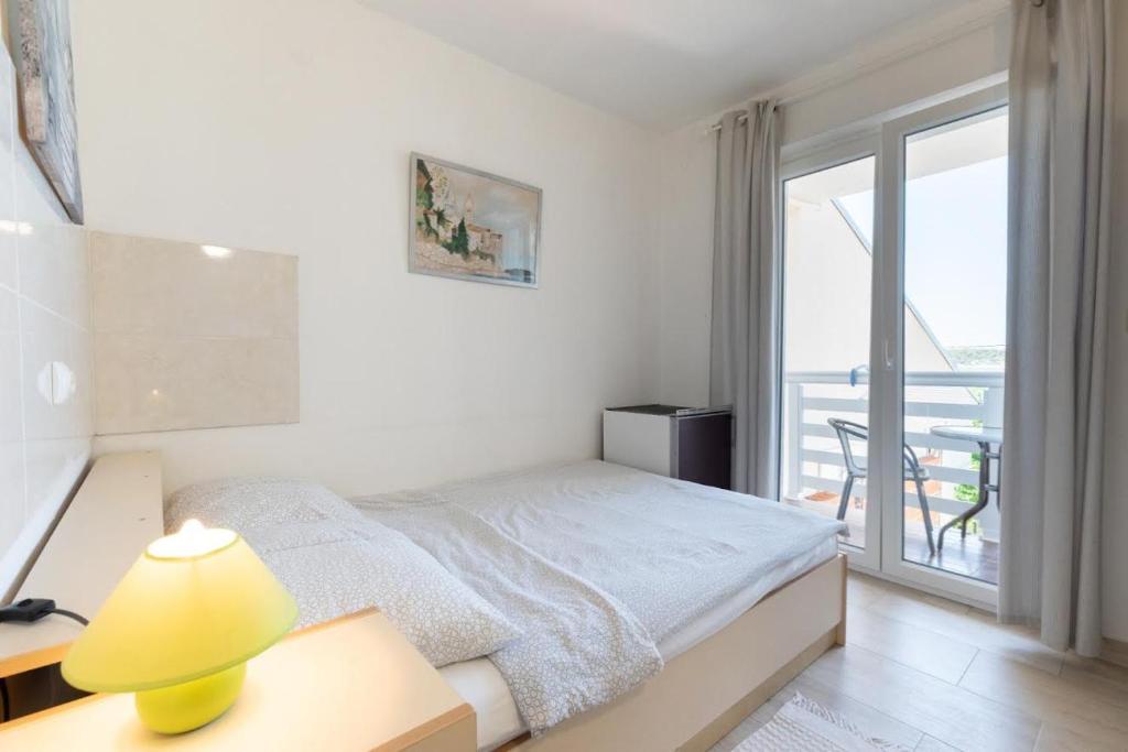 a white bedroom with a bed and a balcony at K&D Home in Rab