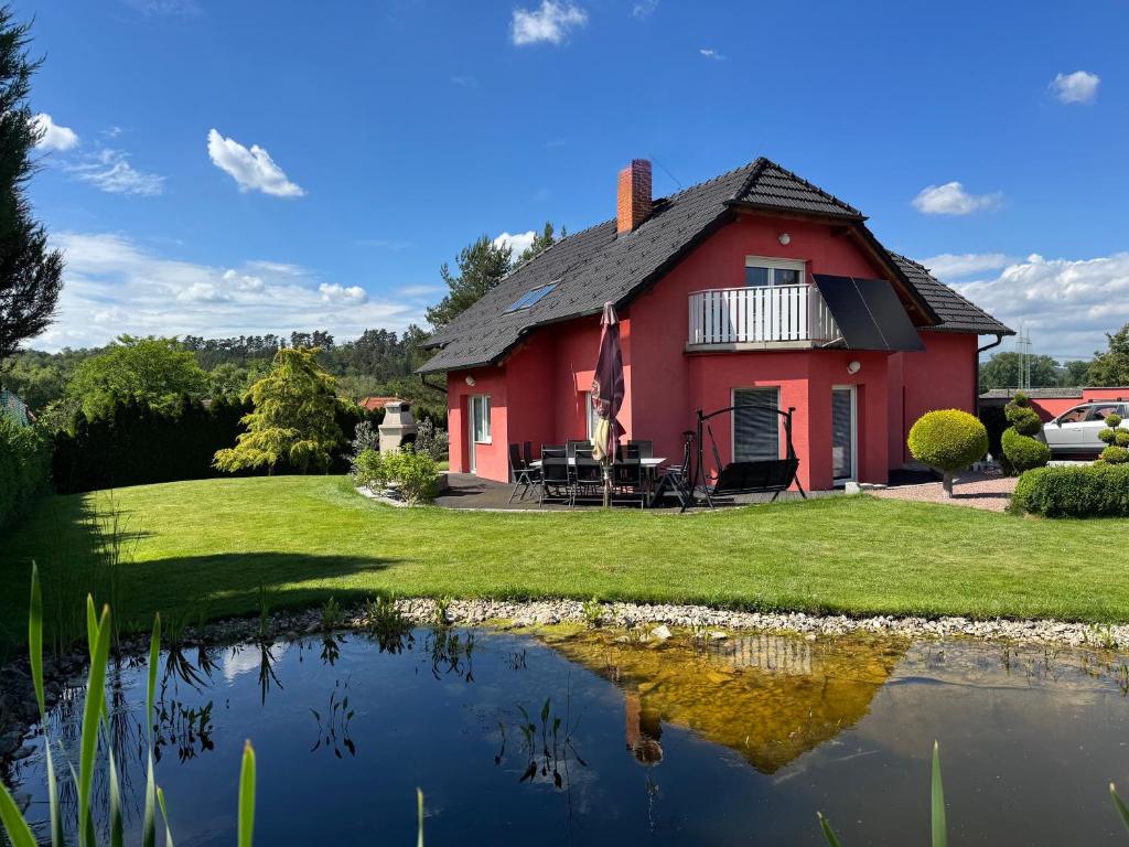 a red house with a pond in front of it at Dům Stašov in Stašov
