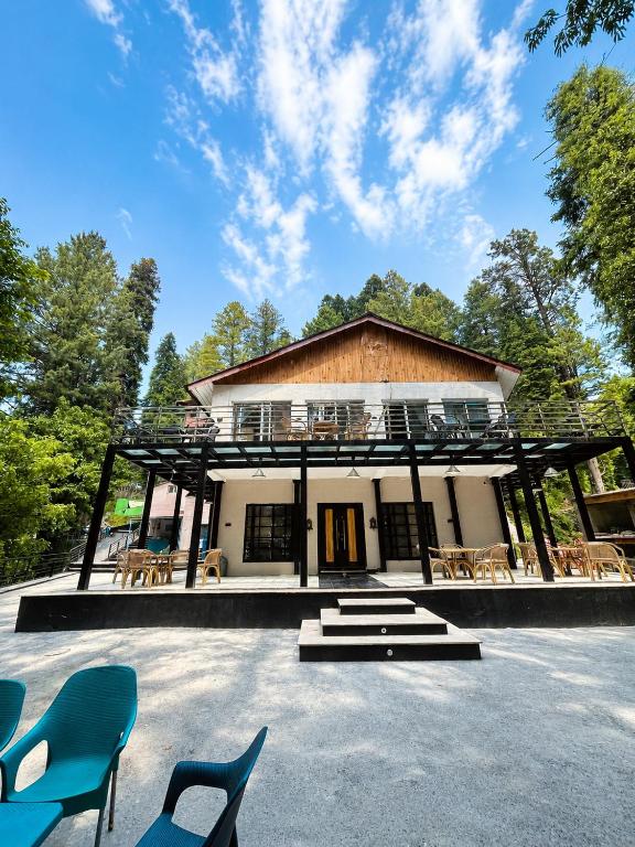 a house with a large building with blue chairs at Hotel Plaza Park in Nathia Gali