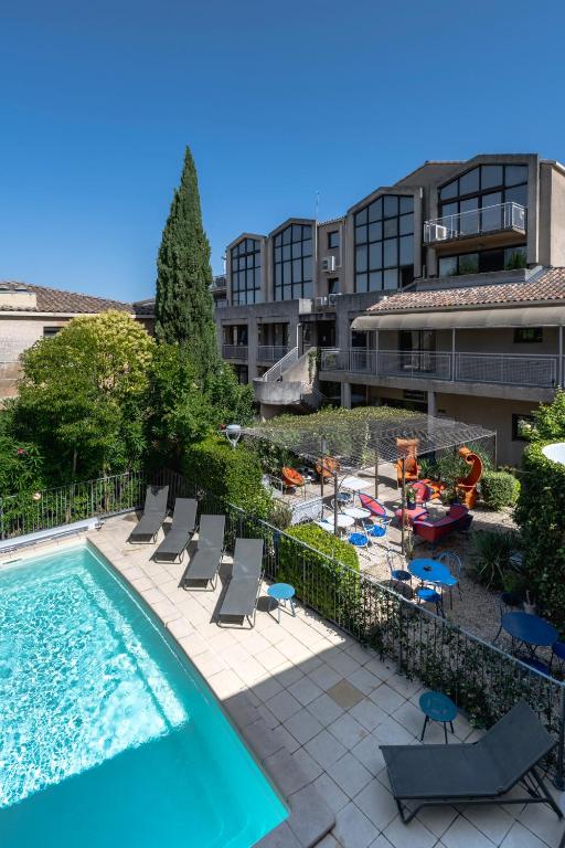 a swimming pool with lounge chairs and a building at Hotel Cantosorgue in L'Isle-sur-la-Sorgue