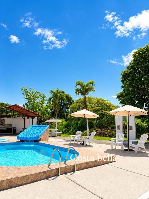 a swimming pool with chairs and umbrellas next to it at Escápate a Jacó apartamento completo in Jacó