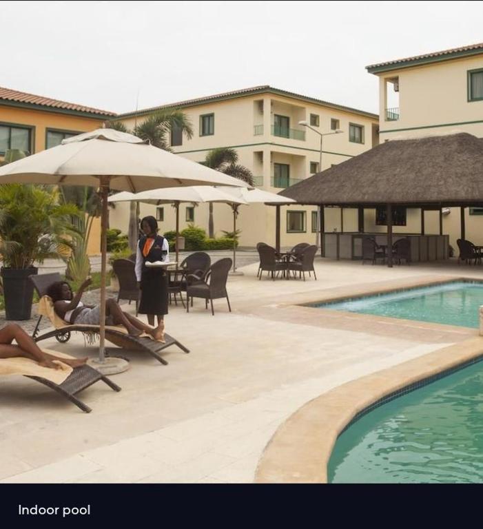 a woman is standing next to a swimming pool at Agentour Guesthouses in Luanda