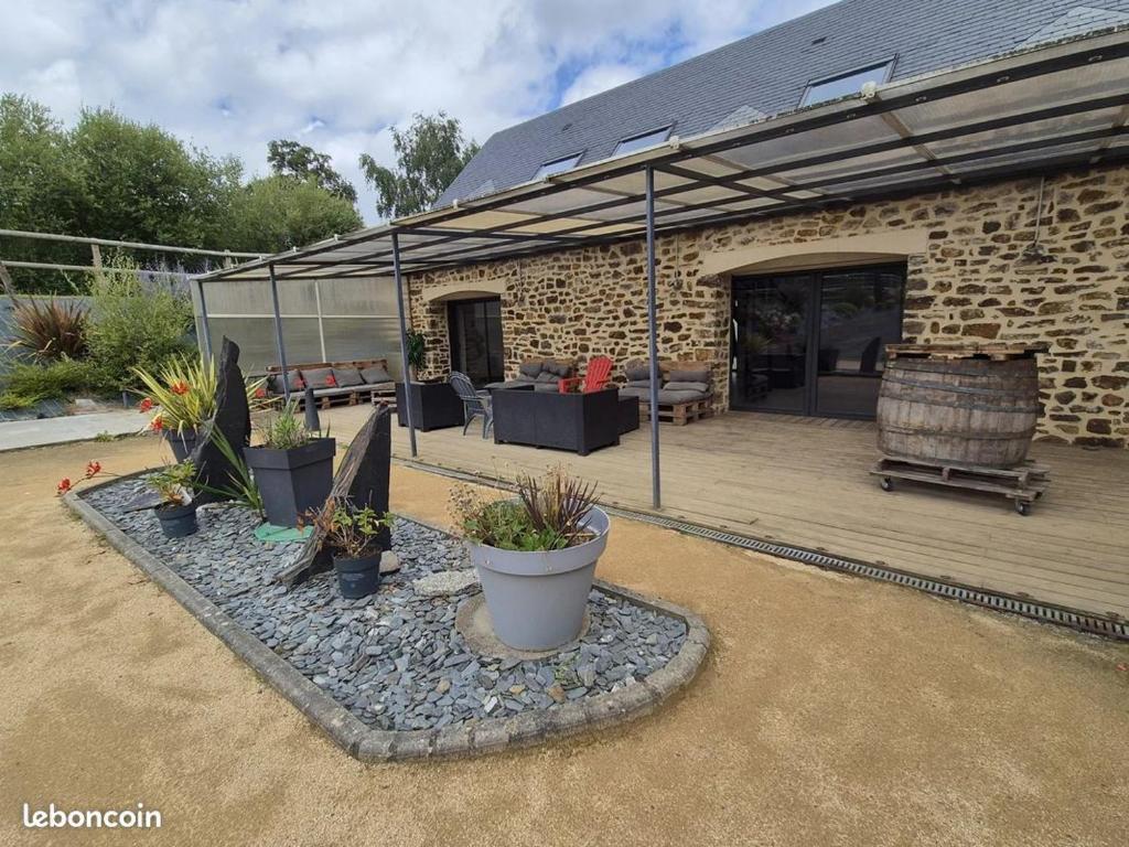 a patio with potted plants in front of a building at Gîte Le petit Fresnay in Le Bourgneuf-la-Forêt