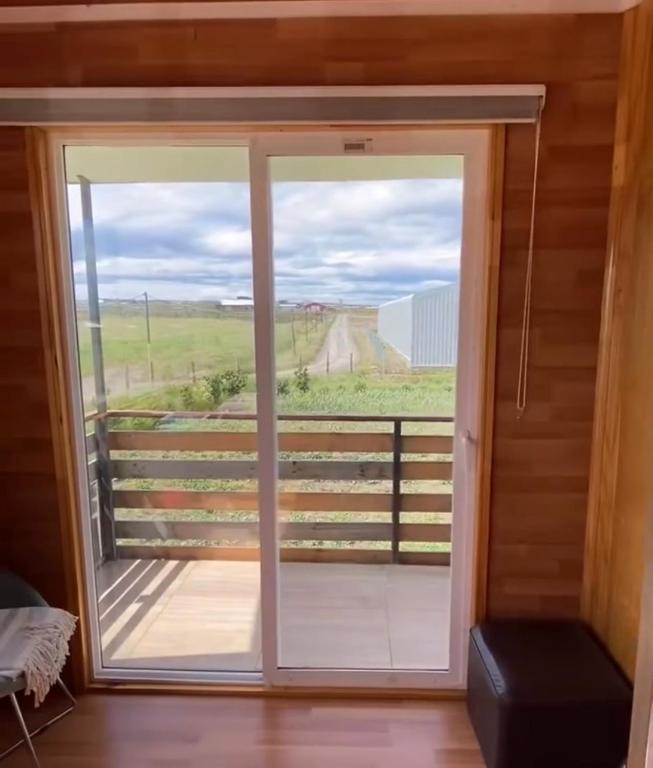 a door leading to a balcony with a view of a field at Depto huerto 23 in Puerto Natales