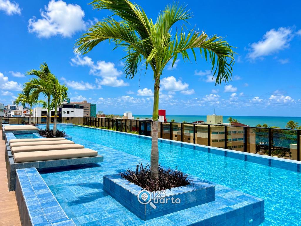 a swimming pool with a palm tree on top of a building at Hit Cabo Branco by 123Quarto in João Pessoa