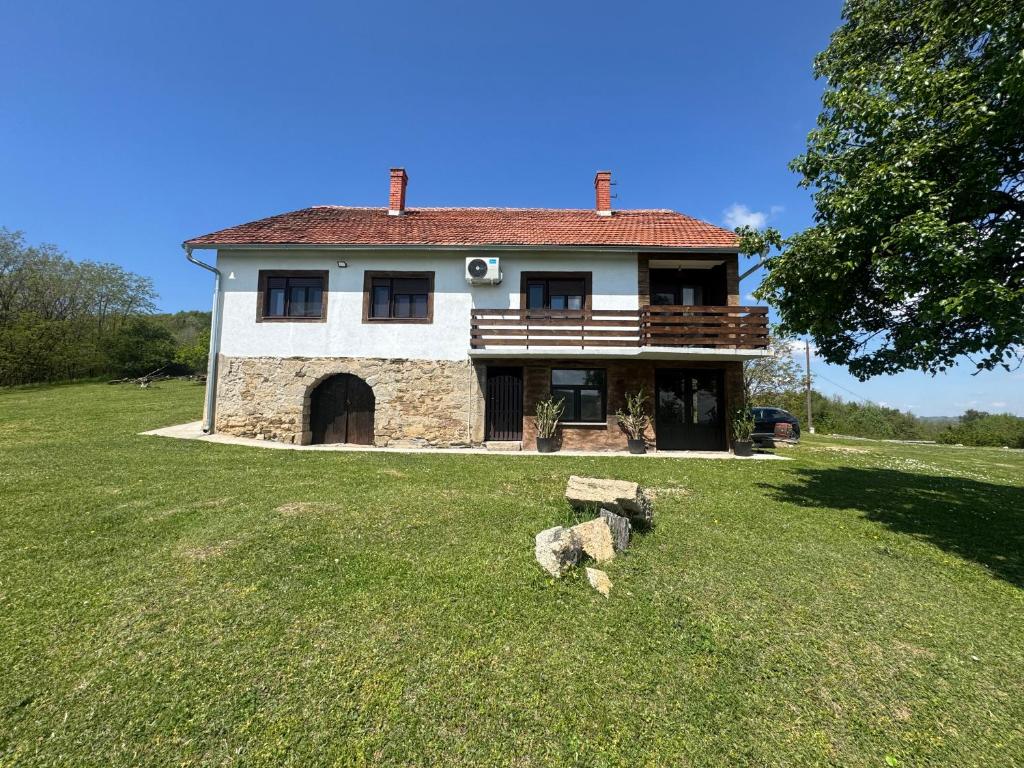 a house with a large yard with a rock in the grass at Imanje Kovačević in Gornji Milanovac